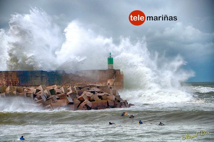 Un grupo de surfistas cabalgan en el puerto de A Guarda en pleno temporal