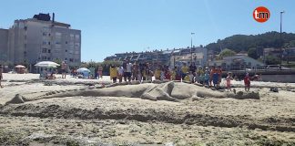 Niños del campamento urbano de Baíña realizan un dragón de arena en la playa de Santa Marta